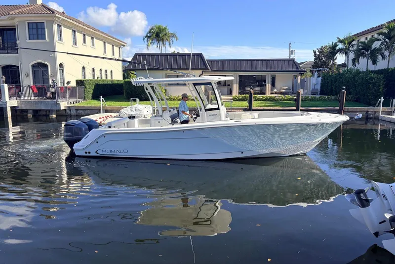 The Image of 2019 Robalo R302 Center Console boat docked in a scenic waterfront setting. - 0