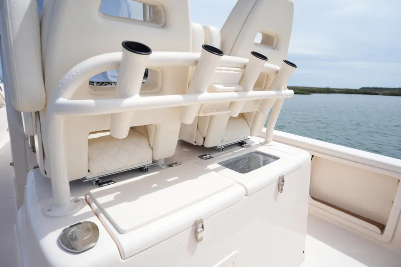 Slide: The Image of 2024 Grady-White 281 Coastal Explorer boat seating with rod holders and storage, on calm water. - 21