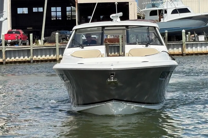 Slide: The Image of 2020 Pursuit DC 365 Dual Console boat on water near dock. - 2