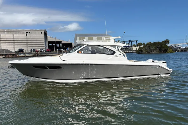 Slide: The Image of 2020 Pursuit DC 365 Dual Console boat on water near industrial buildings. - 4