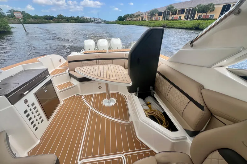 Slide: The Image of 2017 Sea Ray SLX 350 Outboard interior with seating, table, and waterway view. - 18