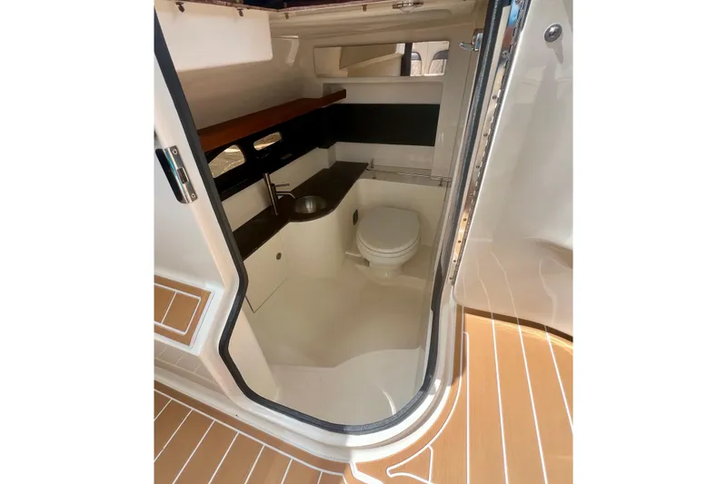 Slide: The Image of Interior of 2017 Sea Ray SLX 350 Outboard, featuring compact bathroom with sink and toilet. - 21