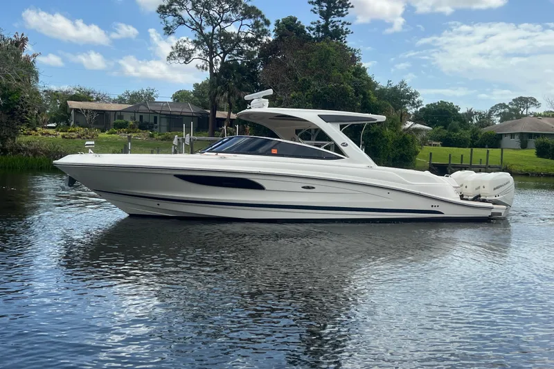Slide: The Image of 2017 Sea Ray SLX 350 Outboard boat on a calm river, surrounded by greenery. - 5