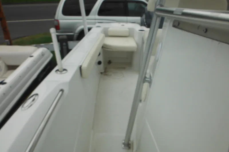 Slide: The Image of 2005 Sailfish 218 CC boat interior with seating and railing, parked near a road. - 17