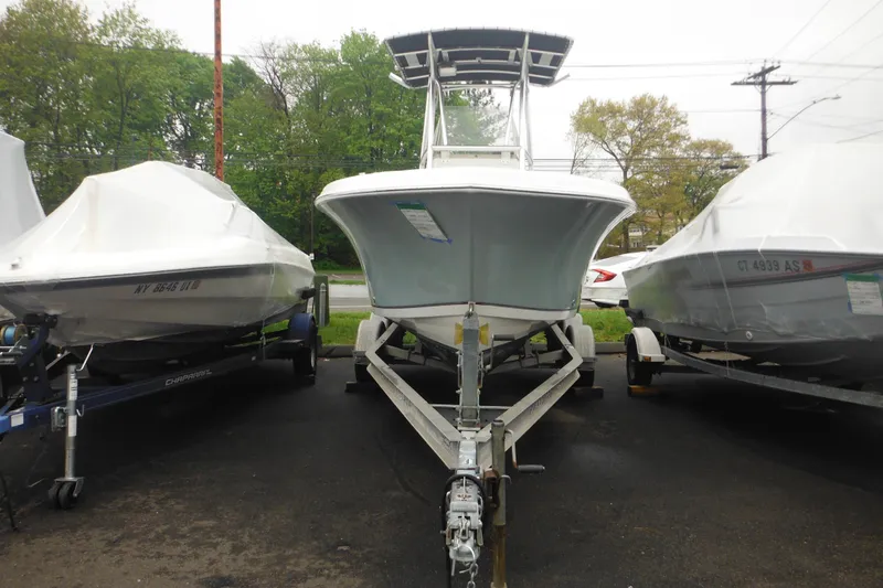 Slide: The Image of 2005 Sailfish 218 CC boat on trailer, parked between two covered boats. - 3