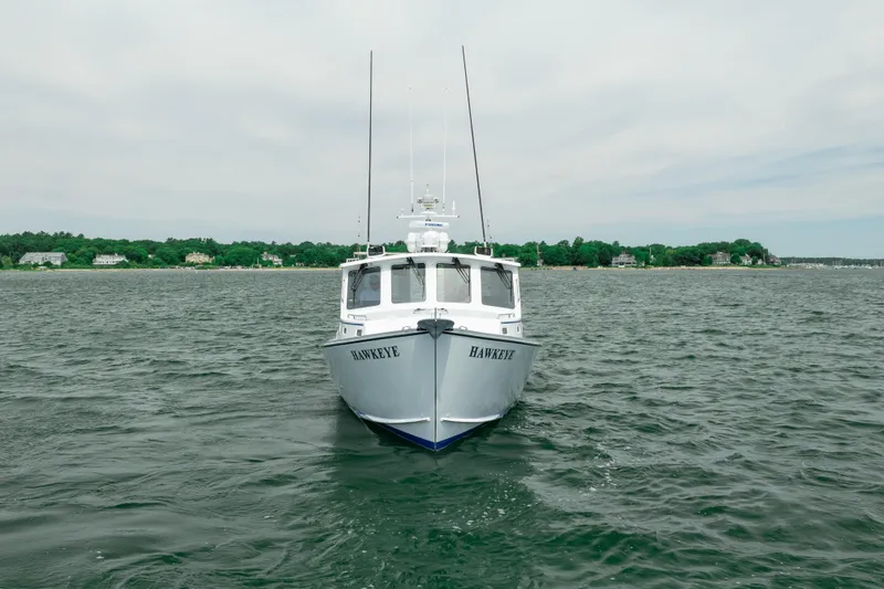 Slide: The Image of 2018 Northern Bay 38 boat named "Hawkeye" on calm waters near a green shoreline. - 4