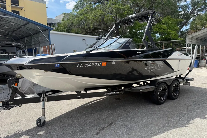 The Image of 2016 Axis A22 boat on trailer, black and white design, parked outdoors. - 0