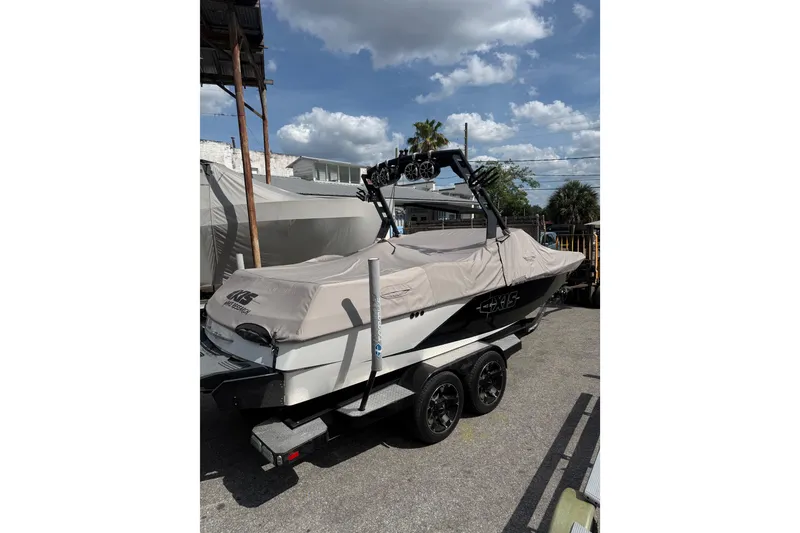 Slide: The Image of 2016 Axis A22 boat on trailer with cover, parked outdoors under blue sky. - 2