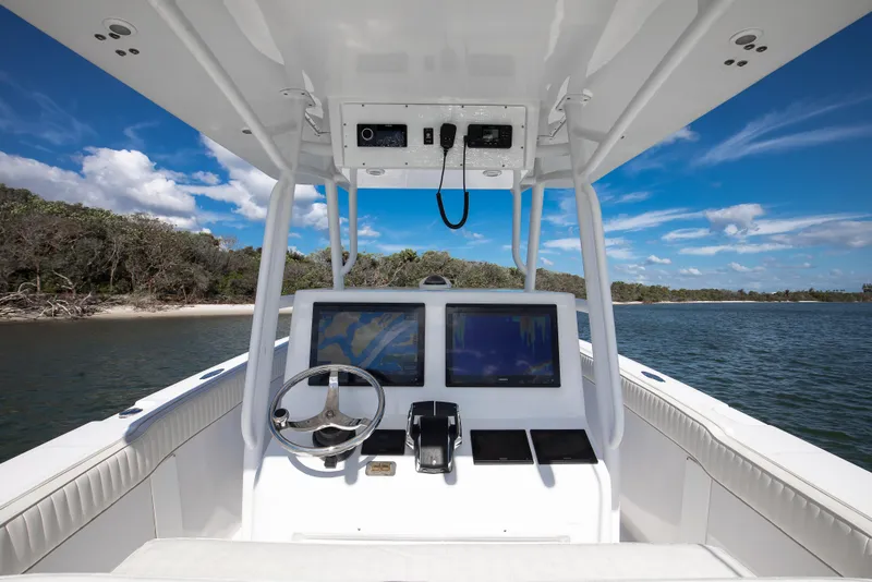 Slide: The Image of Cockpit view of 1997 Marlago 35fs boat with dual screens, steering wheel, and ocean backdrop. - 4