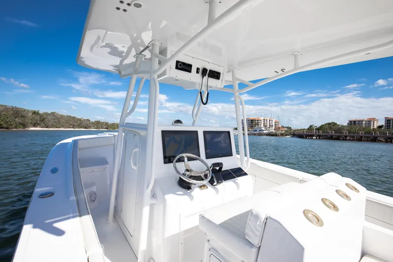 Slide: The Image of 1997 Marlago 35fs boat interior with steering wheel and dual screens, on calm water. - 5