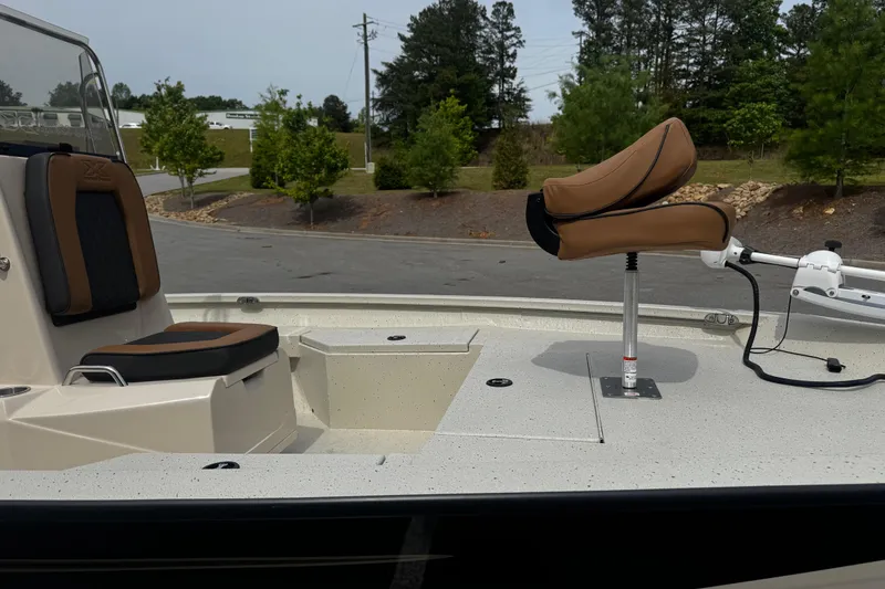 Slide: The Image of 2026 Xpress H20B Bay boat interior with seating and trolling motor, parked outdoors. - 19