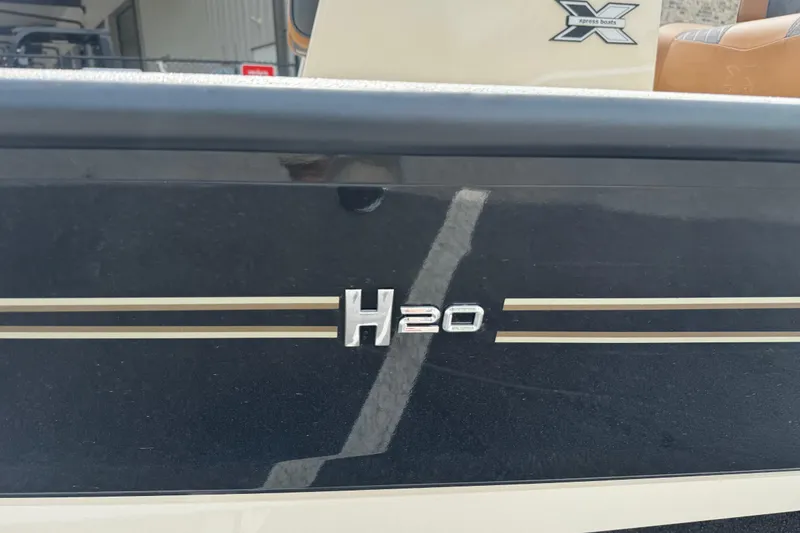 Slide: The Image of 2026 Xpress H20B Bay boat with sleek black and gold detailing. - 2