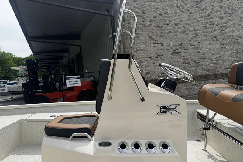 Slide: The Image of 2026 Xpress H20B Bay boat interior with steering console and seating, parked near a brick wall. - 7