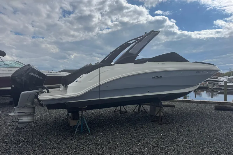 The Image of 2024 Sea Ray SDX 250 Outboard boat on stands, cloudy sky background. - 1