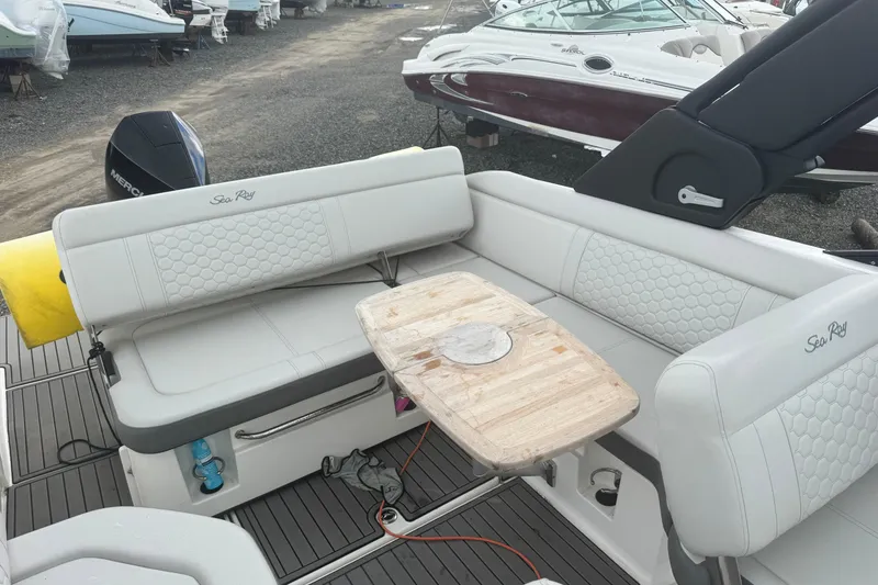 Slide: The Image of 2024 Sea Ray SDX 250 Outboard boat interior with white seating and wooden table. - 7