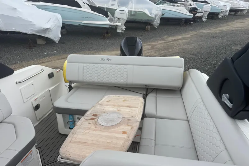 Slide: The Image of 2024 Sea Ray SDX 250 Outboard boat interior with cushioned seating and wooden table. - 8