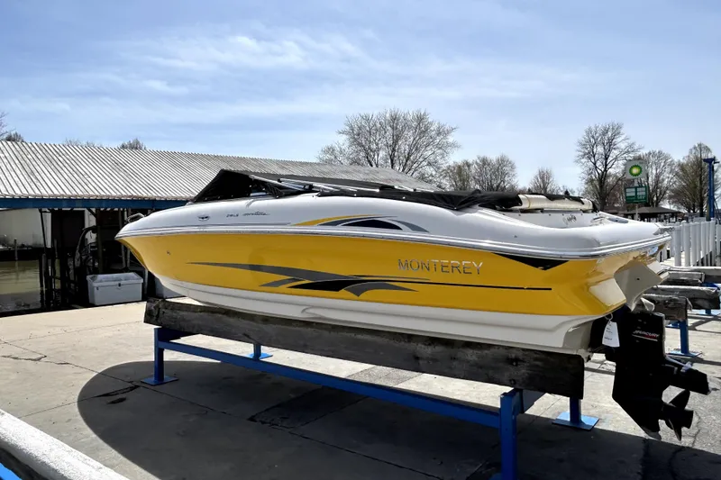 Slide: The Image of 2003 Monterey 218LS Montura Bowrider in yellow, displayed on a boat lift outdoors. - 25