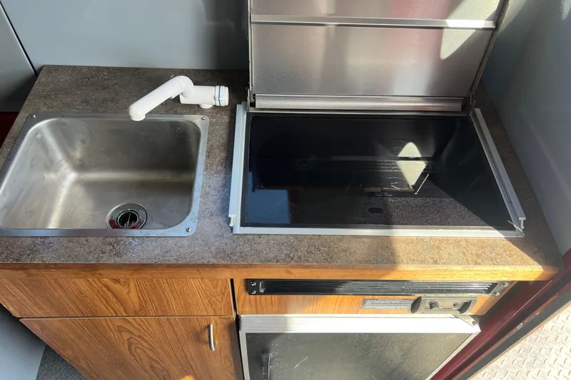 Slide: The Image of Compact kitchen area in a 2018 Hewescraft 240 Pacific Cruiser Hardtop boat. - 12
