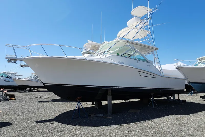The Image of 2009 Cabo 36 Express boat on stands, displayed outdoors under clear blue sky. - 1