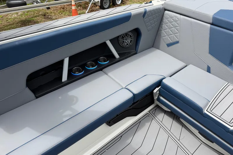 Slide: The Image of 2026 Nautique Super Air Nautique GS24 interior with blue and gray seating and cup holders. - 11