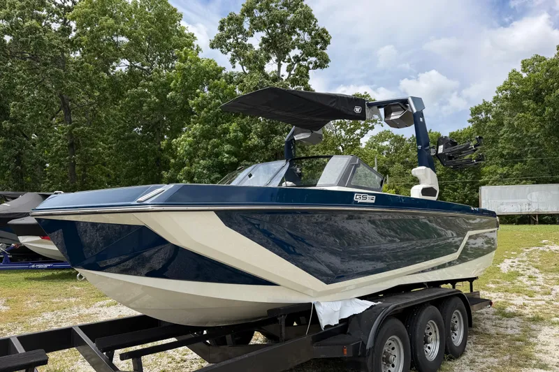 Slide: The Image of 2026 Nautique Super Air Nautique GS24 boat on trailer, surrounded by trees. - 4