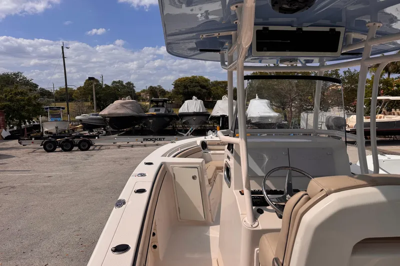Slide: The Image of 2022 Sea Chaser 27 HFC CC boat interior with console and seating, parked outdoors. - 11