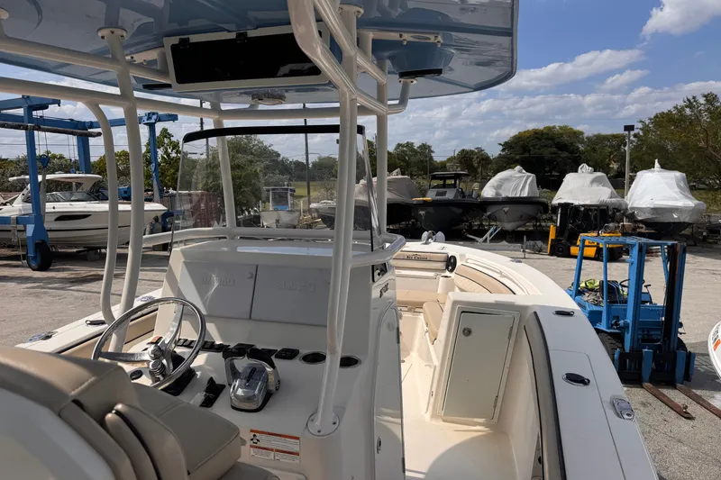 Slide: The Image of 2022 Sea Chaser 27 HFC CC boat interior with steering wheel and controls, docked outdoors. - 12