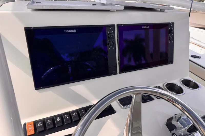 Slide: The Image of 2022 Sea Chaser 27 HFC CC dashboard with dual Simrad displays and steering wheel. - 13