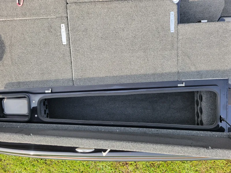 Slide: The Image of Bass Cat Jaguar 2025 boat interior with storage compartment and carpeted flooring. - 24