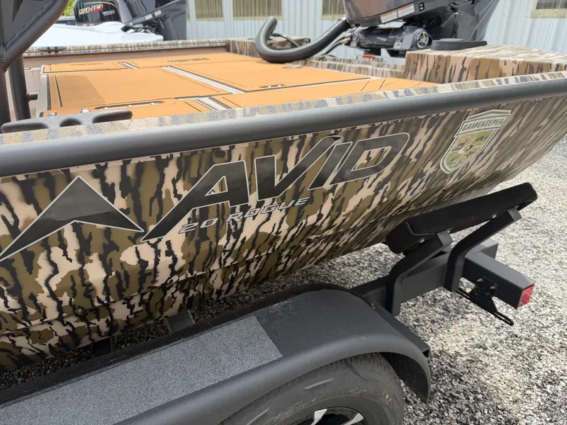 The Image of Avid 20CC Rogue 2026 boat with camouflage design on trailer. - 2