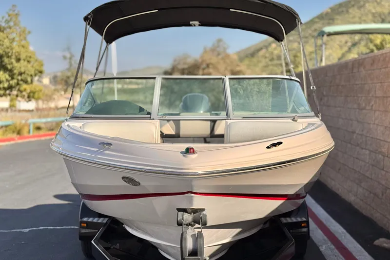 Slide: The Image of 2019 Regal 21 OBX boat with canopy, parked on a trailer, scenic background. - 2