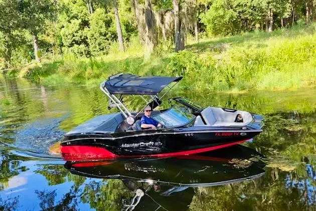 The Image of 2023 MasterCraft NXT20 boat cruising on a scenic river with lush greenery. - 1