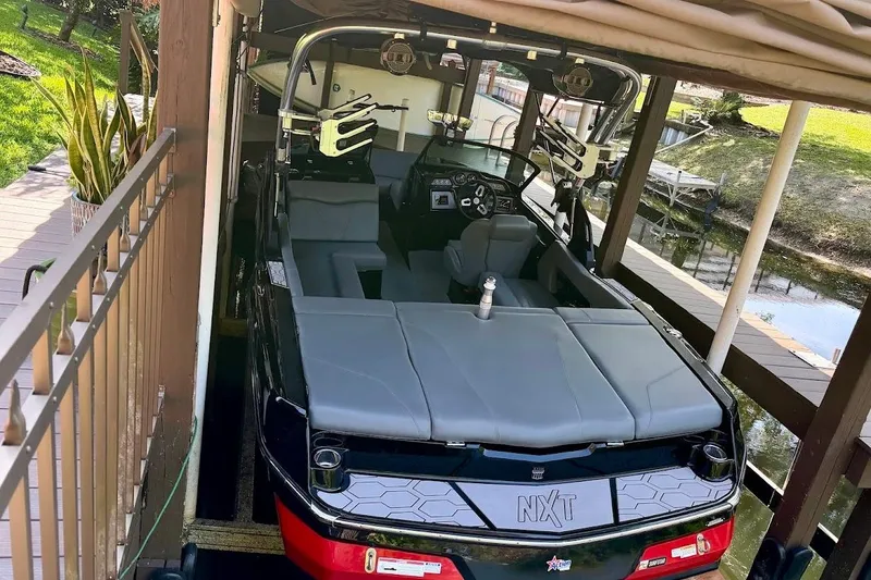 Slide: The Image of 2023 MasterCraft NXT20 boat docked under a canopy, showcasing sleek interior design. - 10