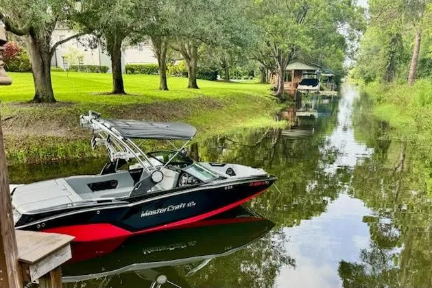 The Image of 2023 MasterCraft NXT20 boat on a serene, tree-lined canal. - 2