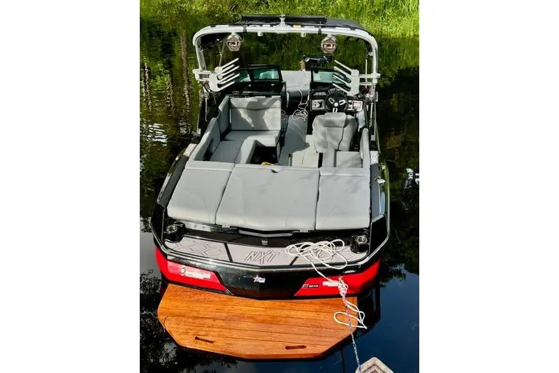 Slide: The Image of 2023 MasterCraft NXT20 boat with gray seating, docked on calm water. - 4