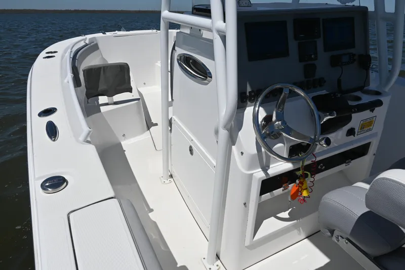 Slide: The Image of 2022 Release 240 RX boat interior with steering console and seating, on calm water. - 33