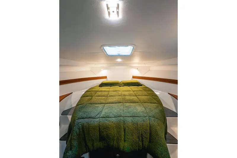 Slide: The Image of Cozy cabin interior of 2024 Lindell 46 with green bedding and overhead lighting. - 43