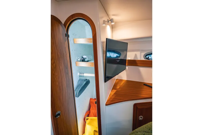 Slide: The Image of 2024 Lindell 46 yacht interior with wooden closet, shelves, and mounted TV. - 44