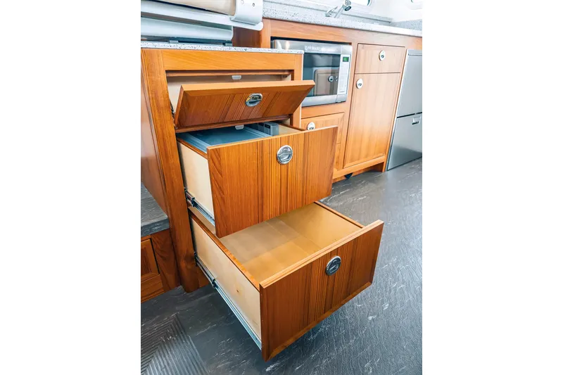 Slide: The Image of Wooden kitchen drawers open in a 2024 Lindell 46 boat interior. - 46