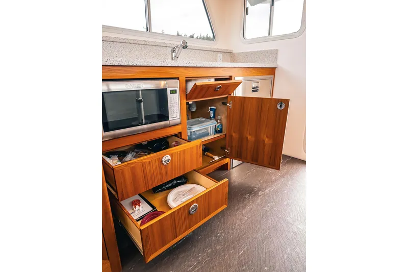 Slide: The Image of Modern kitchen interior in 2024 Lindell 46 boat, featuring wooden cabinets and a microwave. - 49