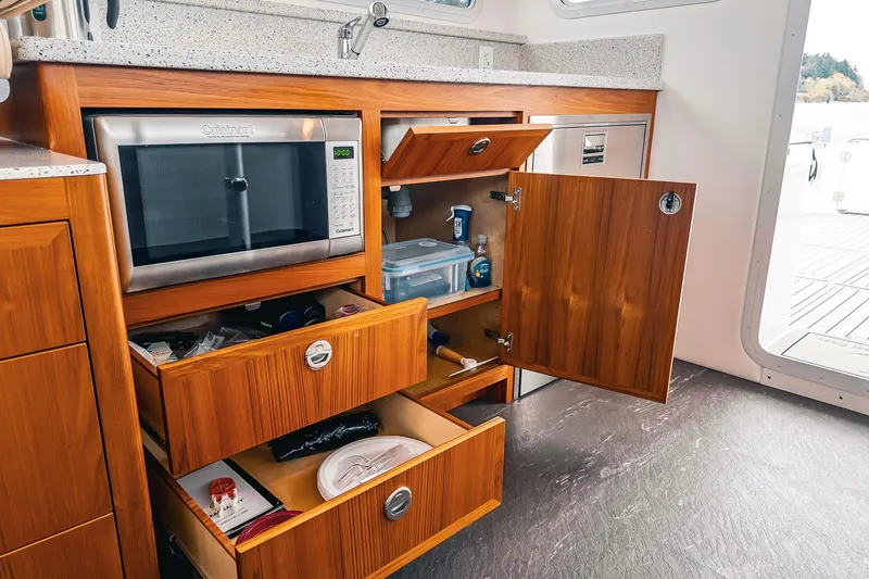 Slide: The Image of Modern Lindell 46 yacht kitchen with wooden cabinetry, microwave, and open storage drawers, 2024 model. - 50