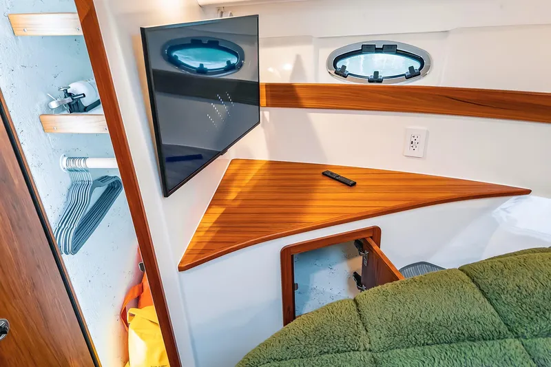 Slide: The Image of 2024 Lindell 46 interior cabin with TV, wooden shelf, and porthole window. - 55