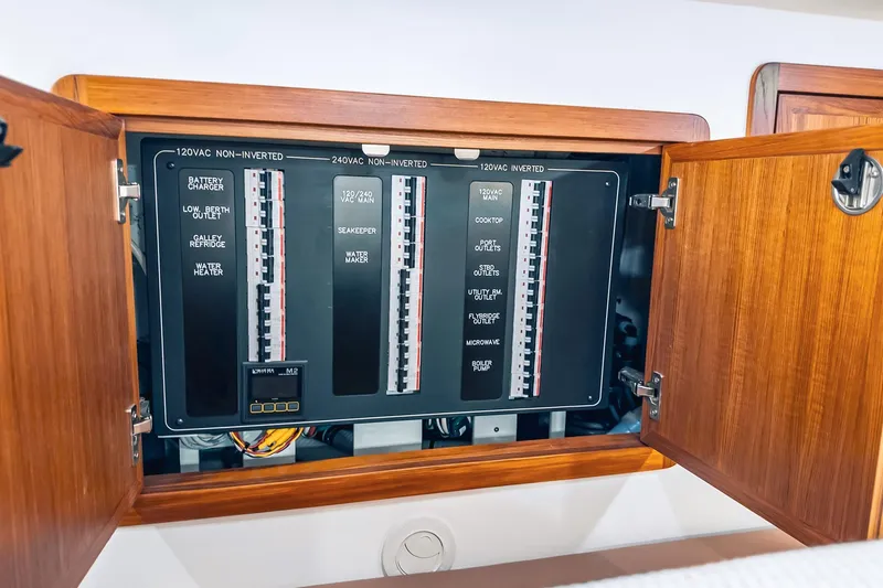 Slide: The Image of Electrical panel inside a 2024 Lindell 46 boat, showcasing circuit breakers and wooden cabinetry. - 58