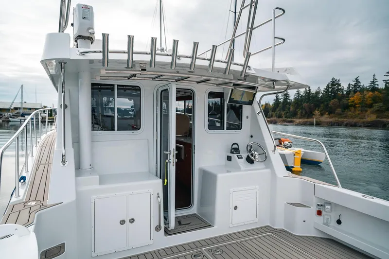 Slide: The Image of 2024 Lindell 46 boat cockpit with steering wheel, docked by a scenic waterfront. - 63