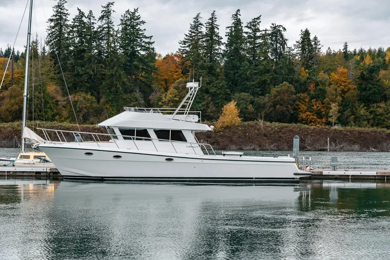 Slide: The Image of 2024 Lindell 46 yacht docked by forested shoreline in serene marina setting. - 92