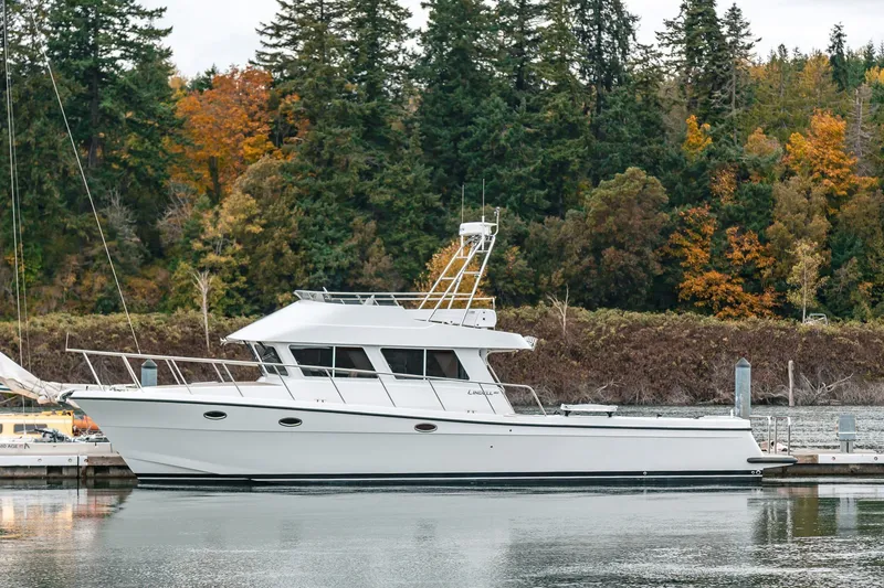 Slide: The Image of 2024 Lindell 46 yacht docked by a forested shoreline in autumn. - 93