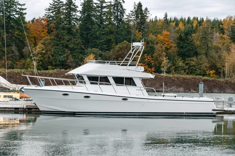 Slide: The Image of 2024 Lindell 46 yacht docked by autumn trees, reflecting on calm water. - 94