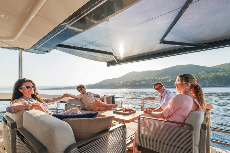 Slide: The Image of People relaxing on a 2026 Absolute 62' Navetta yacht, enjoying scenic ocean views. - 11