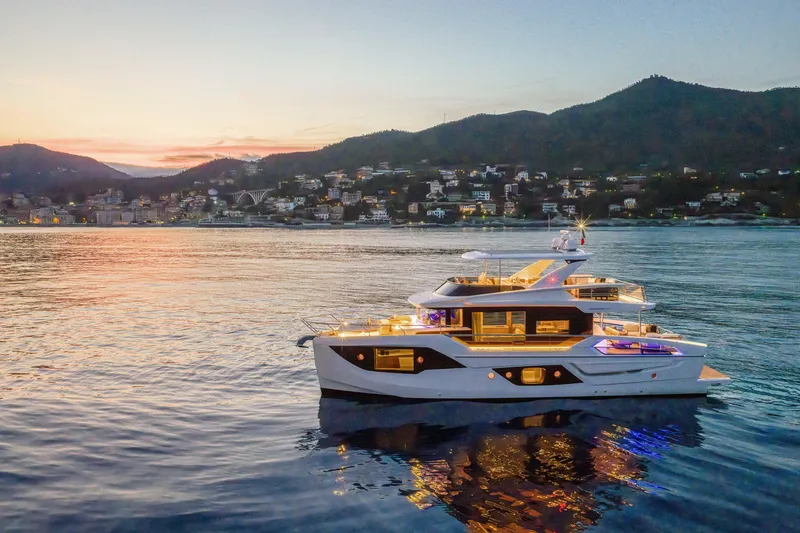 Slide: The Image of Luxurious 2026 Absolute 62' Navetta yacht at sunset, coastal town backdrop. - 4