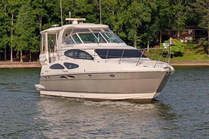 Slide: The Image of 2008 Cruisers Yachts 415 Express Motoryacht on a serene lake with lush greenery. - 2